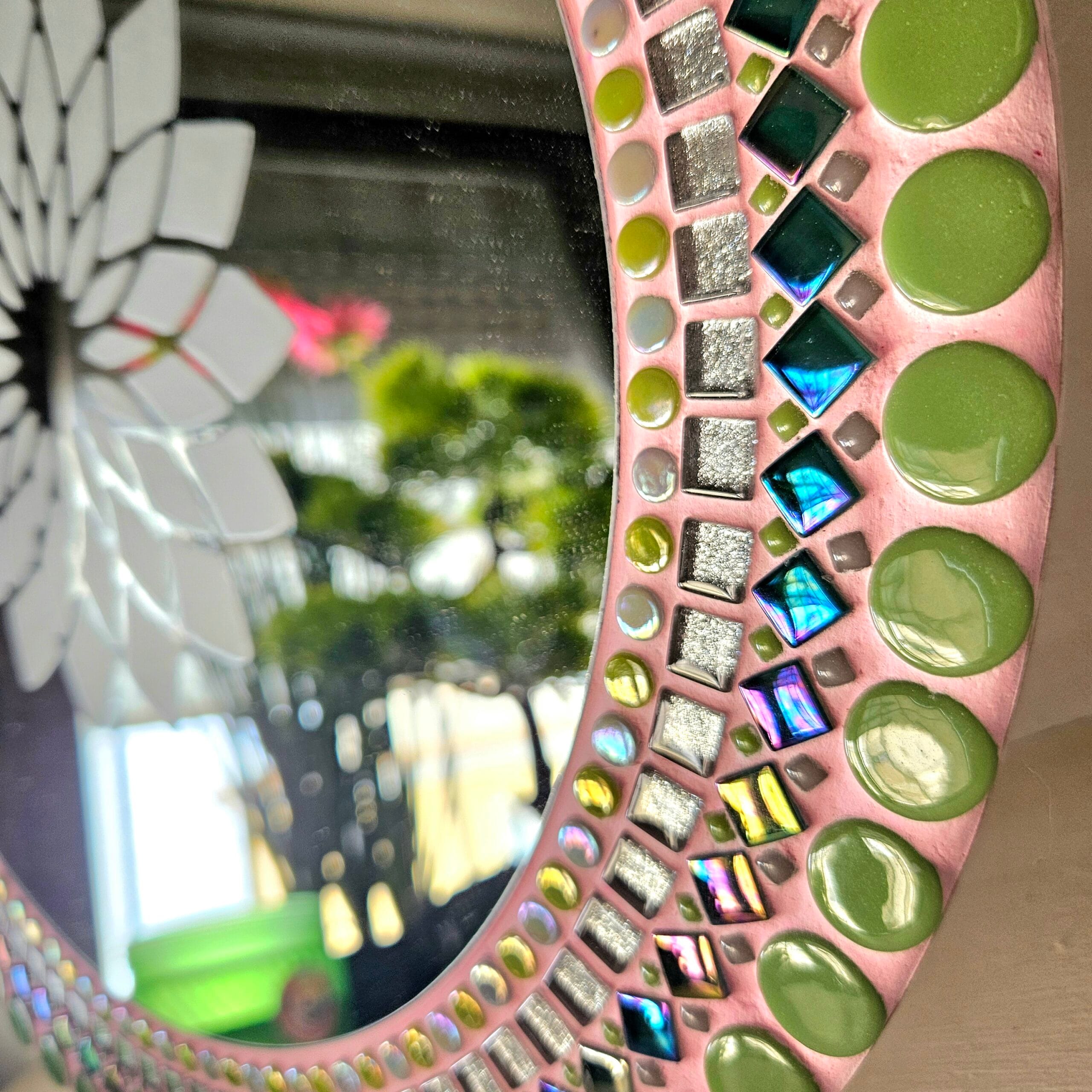 Pink mosaic mirror with green, silver and metallic tiles.