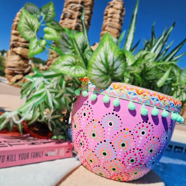 Large pink dotted plant pot decorated with aztec trim.